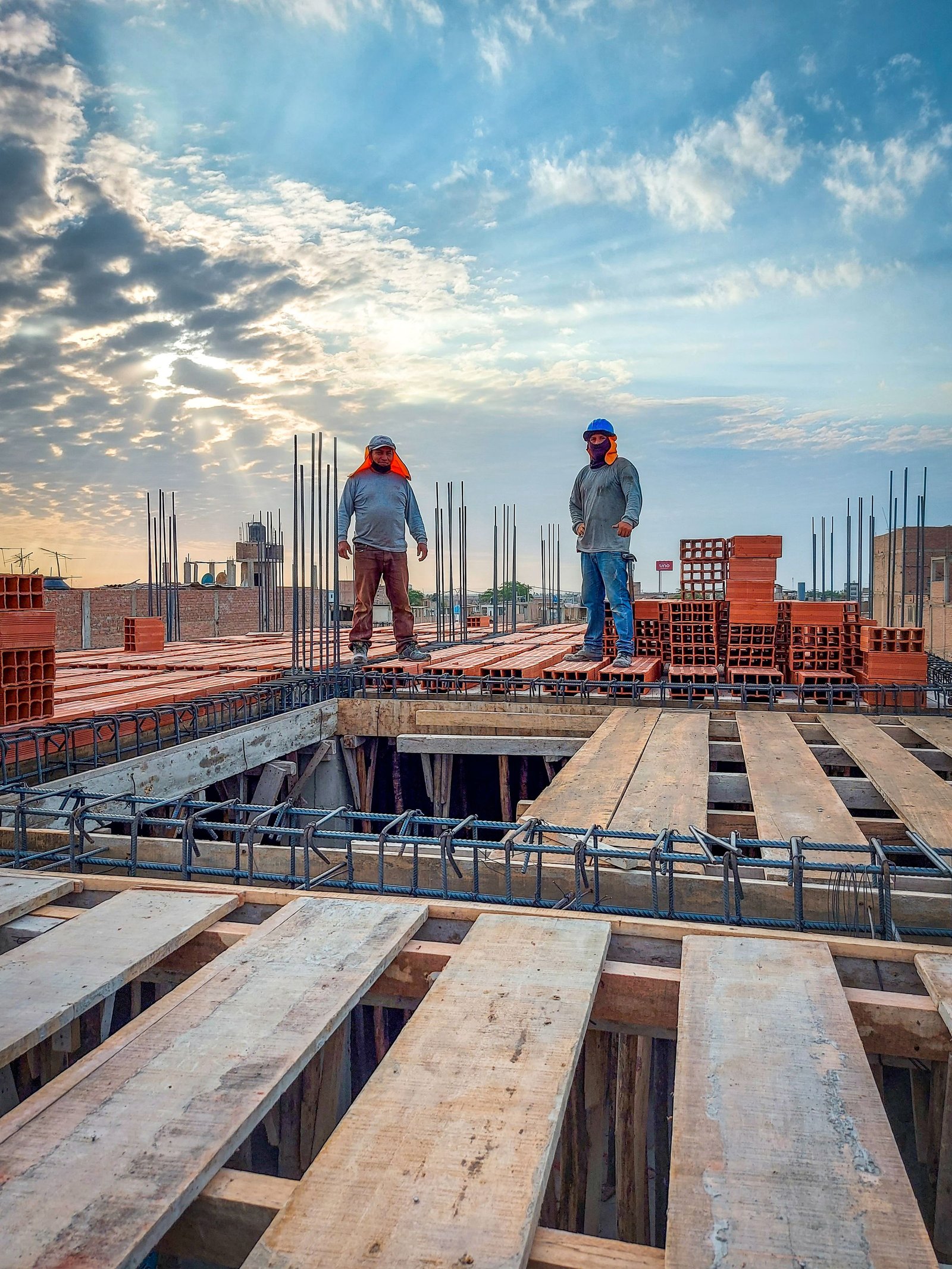 Construction site at sunrise with workers on a rebar and formwork slab